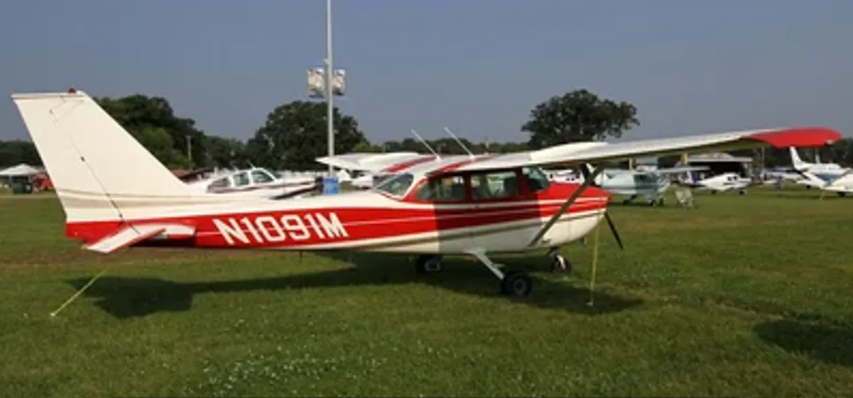 A small red and white plane sitting on top of grass.