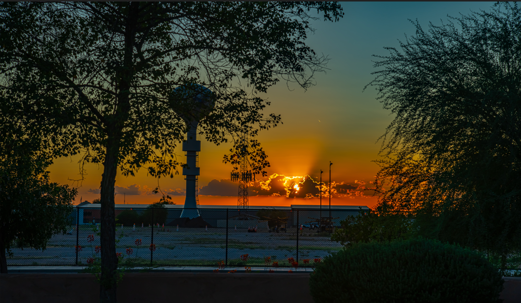 A sunset with the sun setting behind clouds.