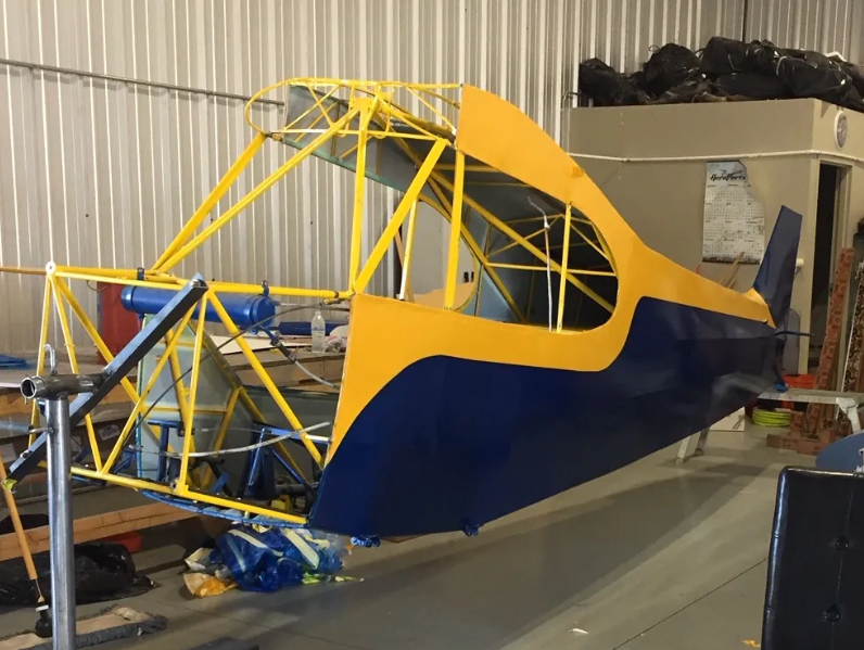 A blue and yellow plane sitting in a hangar.